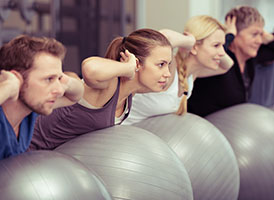 Mehrere Personen liegen bäuchlings auf Gymnastikbällen